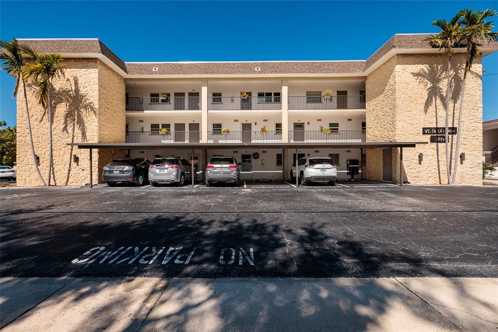 A three-story apartment building features a covered parking area with four cars parked underneath — 3789 46TH AVENUE S UNIT 101, ST PETERSBURG, FL