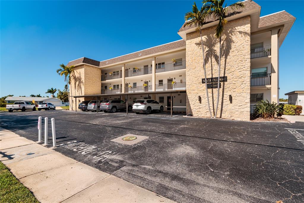 A three-story apartment building with a stone facade, covered parking, and palm trees — 3789 46TH AVENUE S UNIT 101, ST PETERSBURG, FL