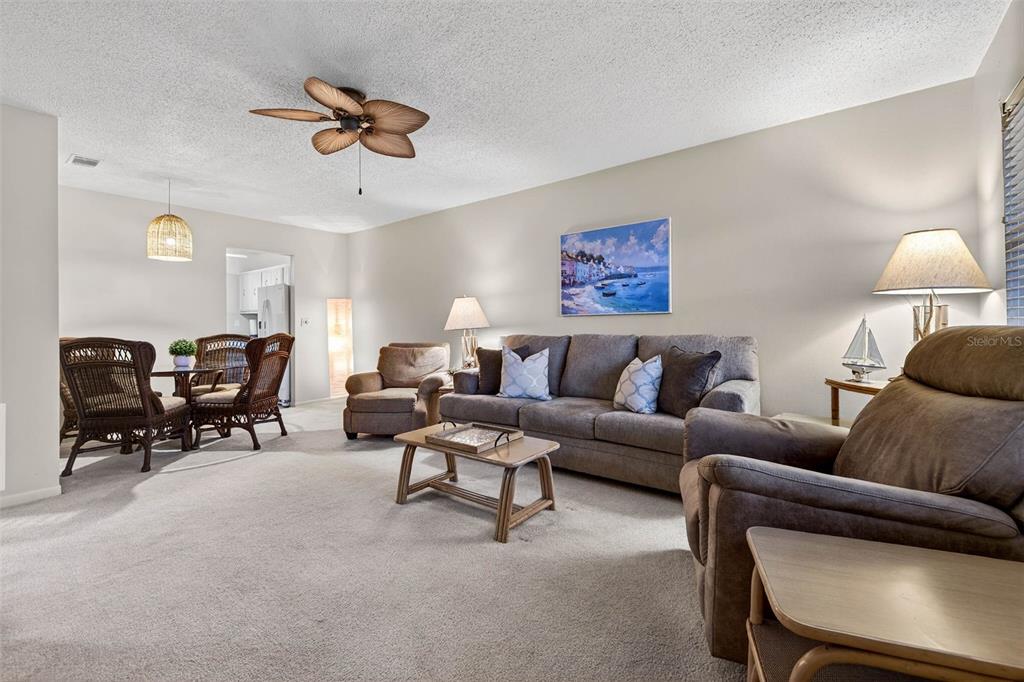 A living room features a gray sofa, two armchairs, a coffee table, and a dining area — 5267 81ST STREET N UNIT 18, ST PETERSBURG, FL