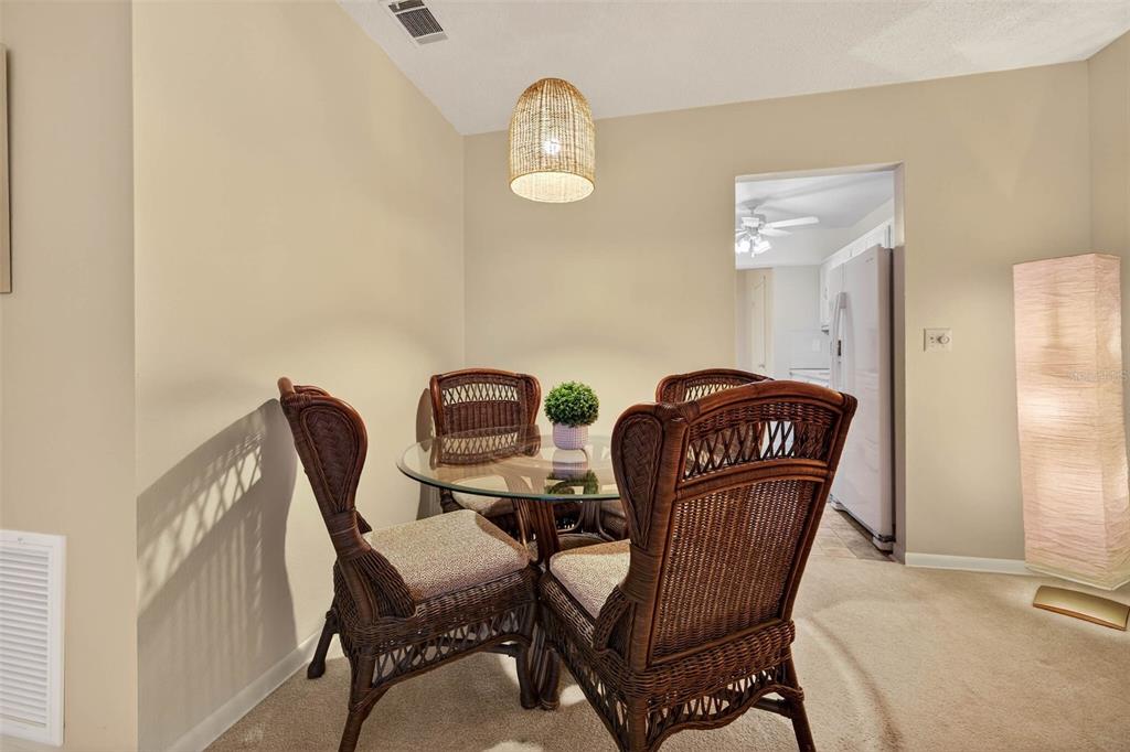 A dining area features a glass-topped table with four wicker chairs under a pendant light — 5267 81ST STREET N UNIT 18, ST PETERSBURG, FL