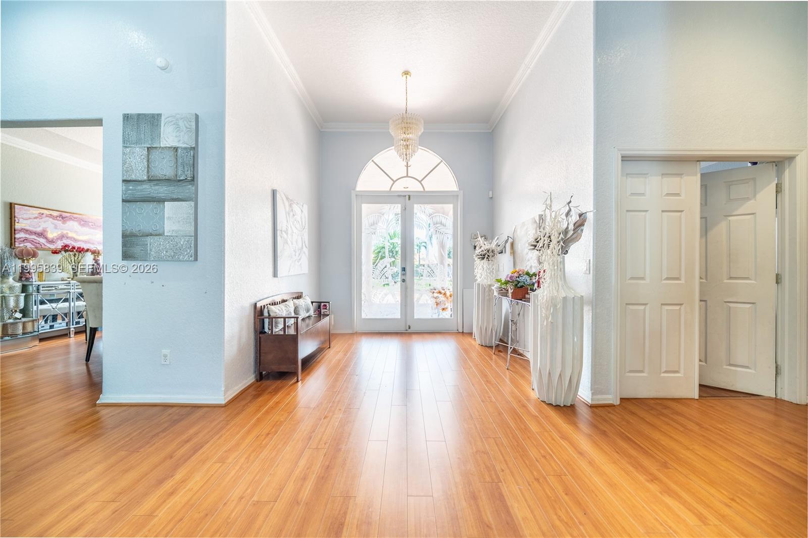 A bright foyer features light wood flooring, a crystal chandelier, and double glass entry doors — 5303 SW 111th Ter, Davie FL 33328, DAVIE, FL