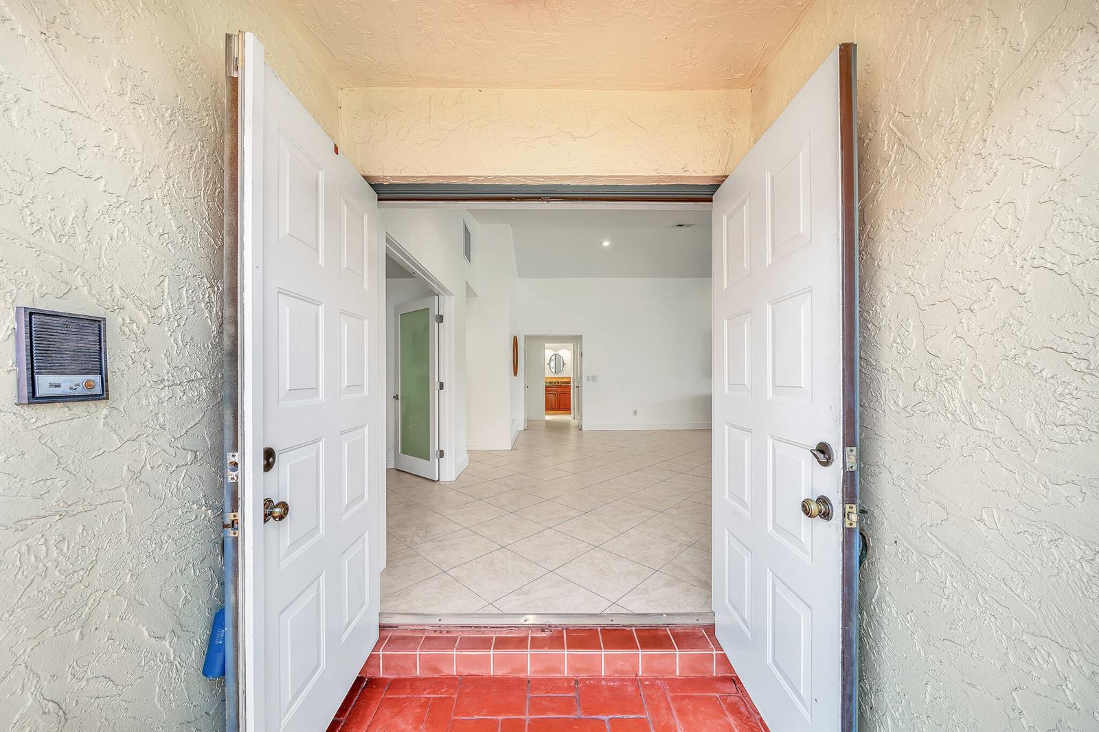 A view through an open double door into a tiled entryway with white interior walls — 10255 Sunset Bend Drive, Boca Raton FL 33428, BOCA RATON, FL
