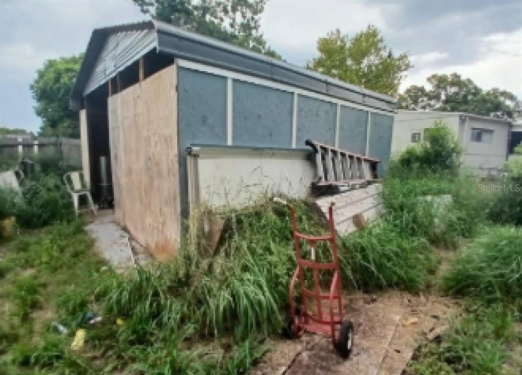 An exterior view of a weathered shed with plywood siding and a metal roof — 6952 POMPEII ROAD, ORLANDO, FL
