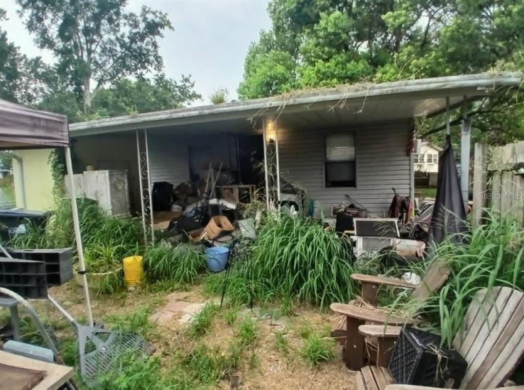 A cluttered porch and yard area in front of a weathered, single-story residential structure — 6952 POMPEII ROAD, ORLANDO, FL