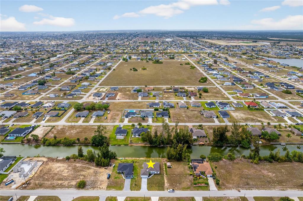An aerial view shows a single-family home with a yellow star on a canal — 2210 NW 2ND AVENUE, CAPE CORAL, FL