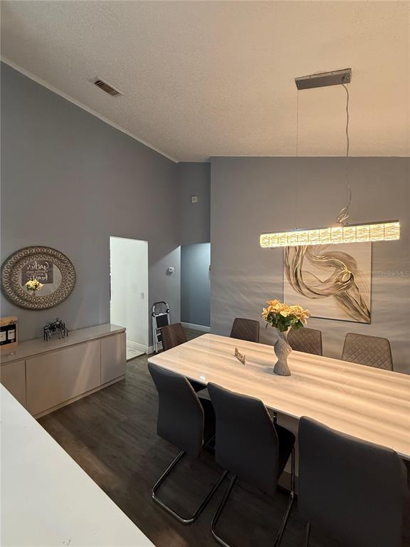 A dining room features a long table, modern chairs, a pendant light, and gray walls — 7736 ROLLINGRIDGE COURT, ORLANDO, FL
