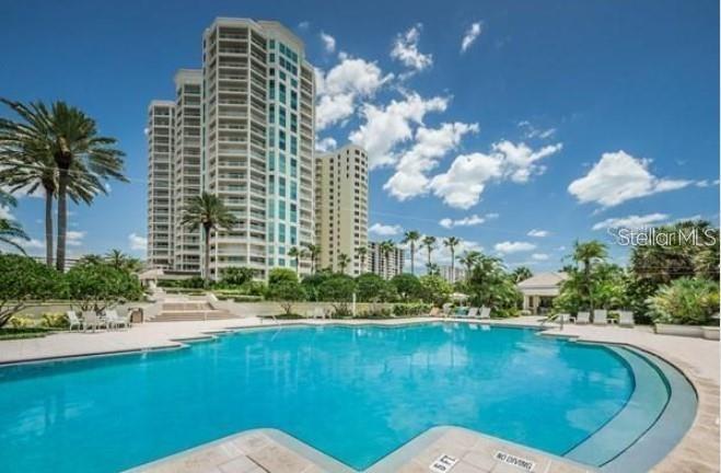 A large swimming pool sits in front of a tall residential high-rise building — 1180 GULF BLVD UNIT 306, CLEARWATER, FL