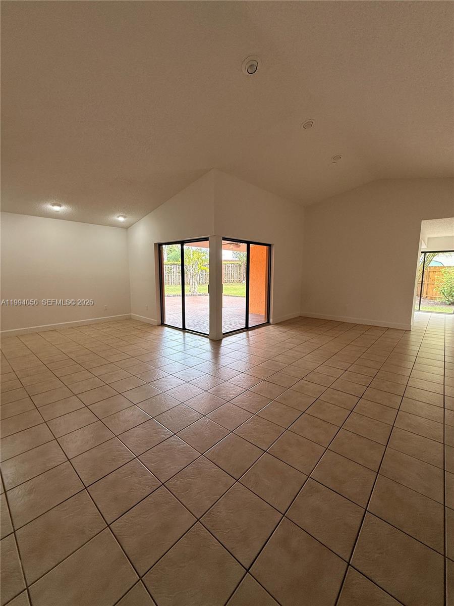 An empty room features light-colored tile flooring, white walls, and sliding glass doors to a patio — 14729 SW 53rd Ter, Miami FL 33185, MIAMI, FL