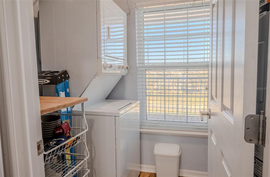 A laundry room features a stacked washer and dryer, a wire shelving unit, and a window — 502 MAIN STREET UNIT 207, HORSESHOE BEACH, FL