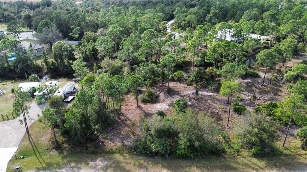 An aerial view of a wooded lot with a gravel driveway and several parked trailers — 13599 CAROUSEL DRIVE, PUNTA GORDA, FL
