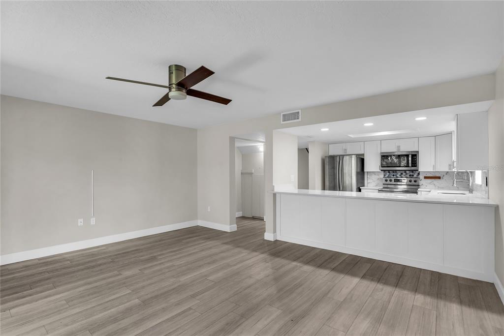 An open-concept living area features light wood-look flooring, a ceiling fan, and a white kitchen — 189 OAK LANE, FLAGLER BEACH, FL