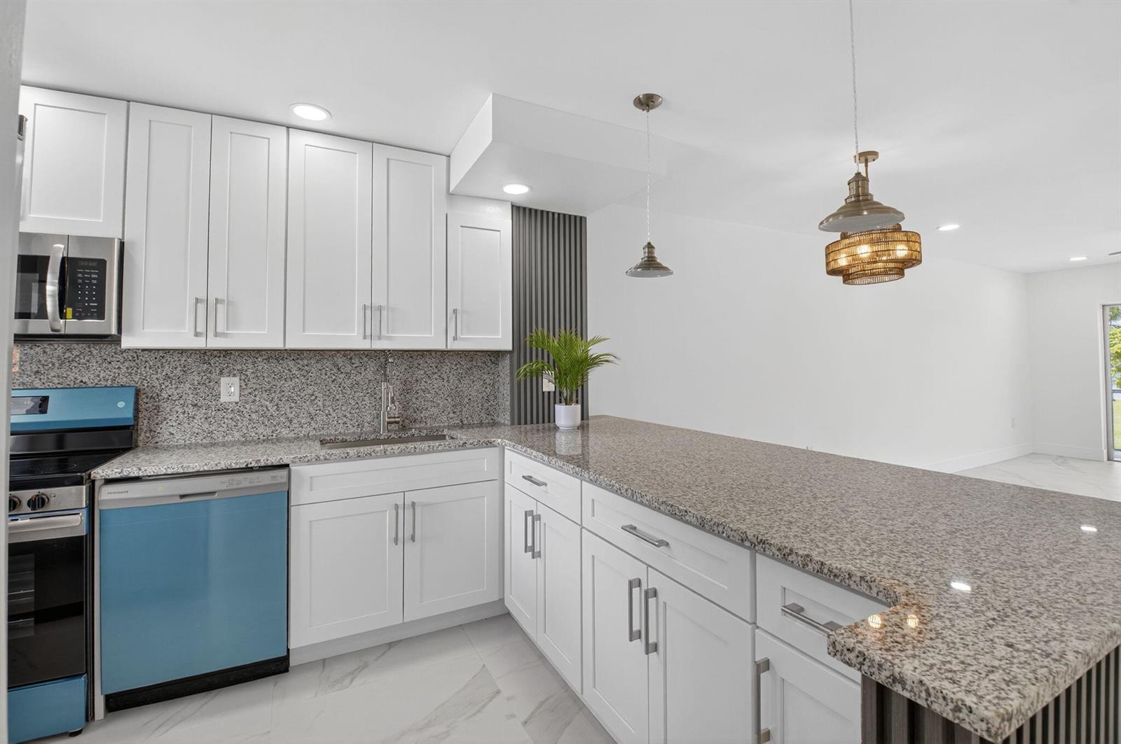 A kitchen with white cabinets, granite countertops, a blue dishwasher, and a breakfast bar — 9886 Marina Boulevard # 622, Boca Raton FL 33428, BOCA RATON, FL