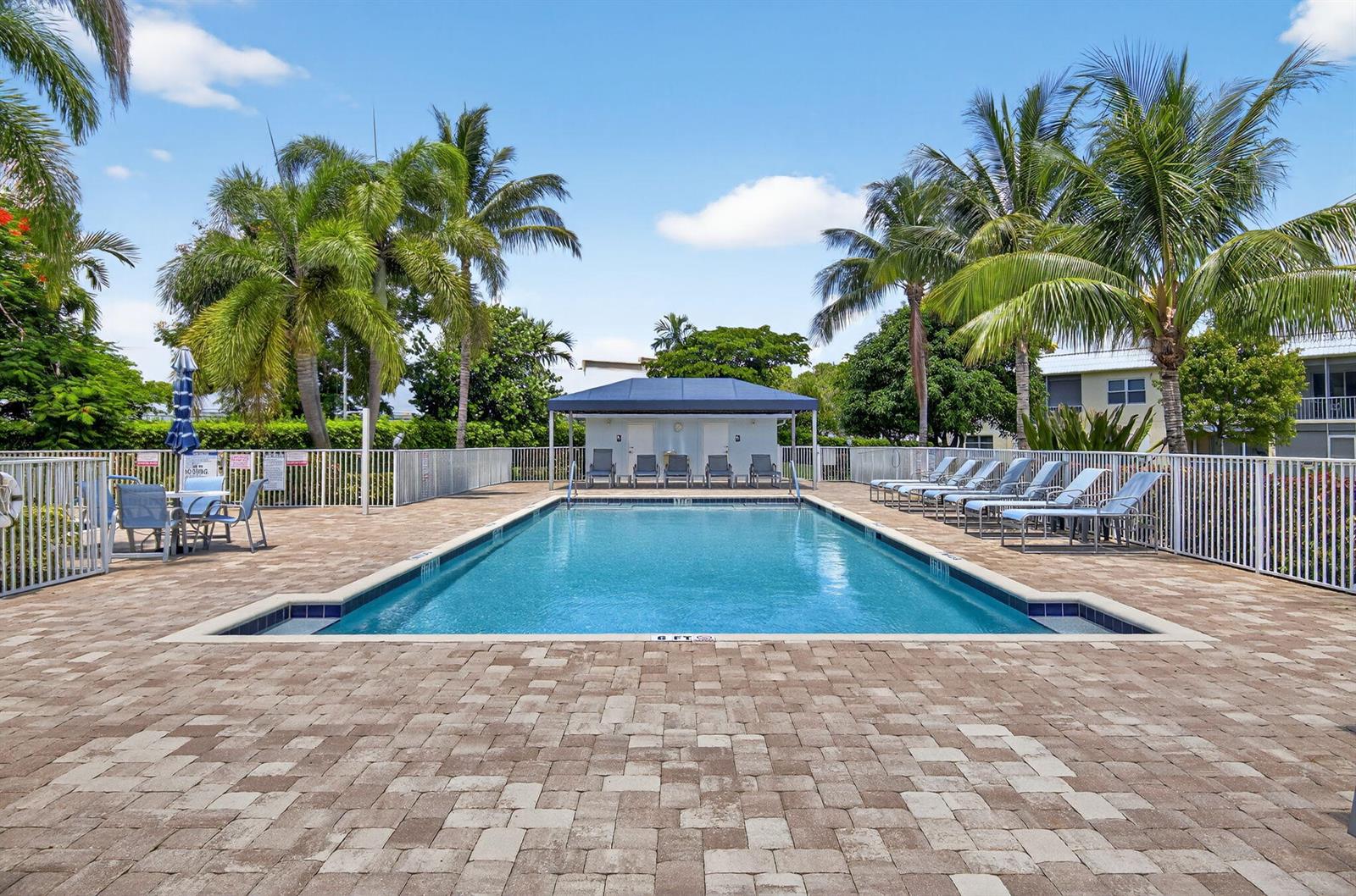 An outdoor swimming pool surrounded by a paved deck, lounge chairs, and palm trees — 9886 Marina Boulevard # 622, Boca Raton FL 33428, BOCA RATON, FL