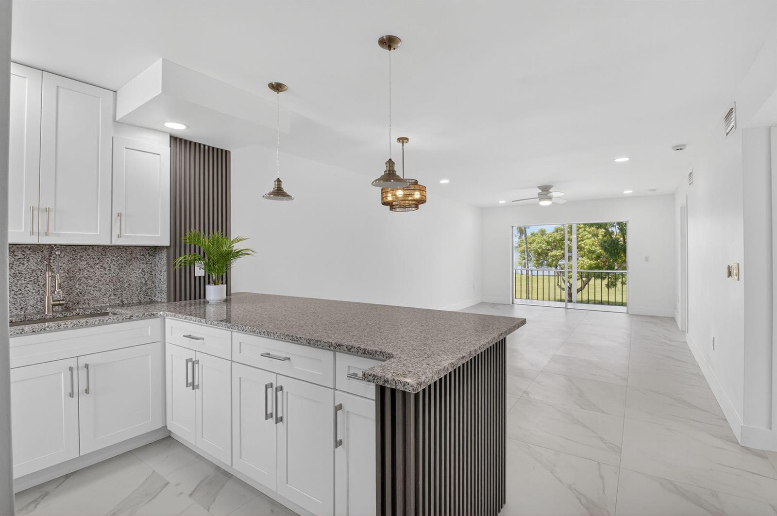 A modern kitchen with white cabinets, granite countertops, and a slatted wood island peninsula — 9886 Marina Boulevard # 622, Boca Raton FL 33428, BOCA RATON, FL