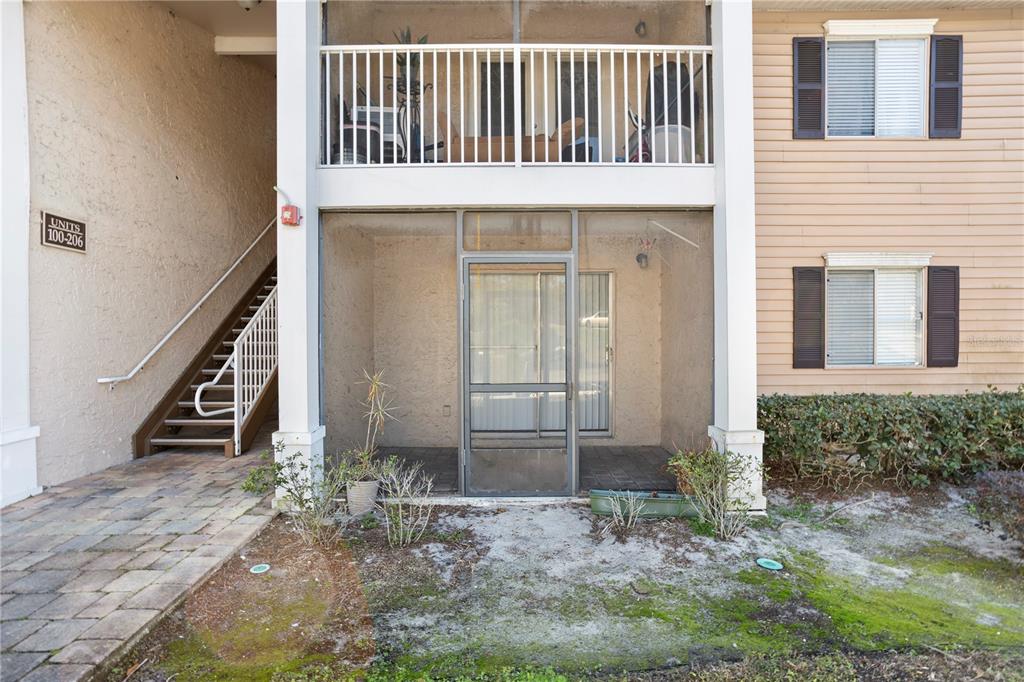 A ground-floor screened patio sits beneath a balcony next to an outdoor staircase — 145 N PEARL LAKE CAUSEWAY UNIT 106, ALTAMONTE SPRINGS, FL