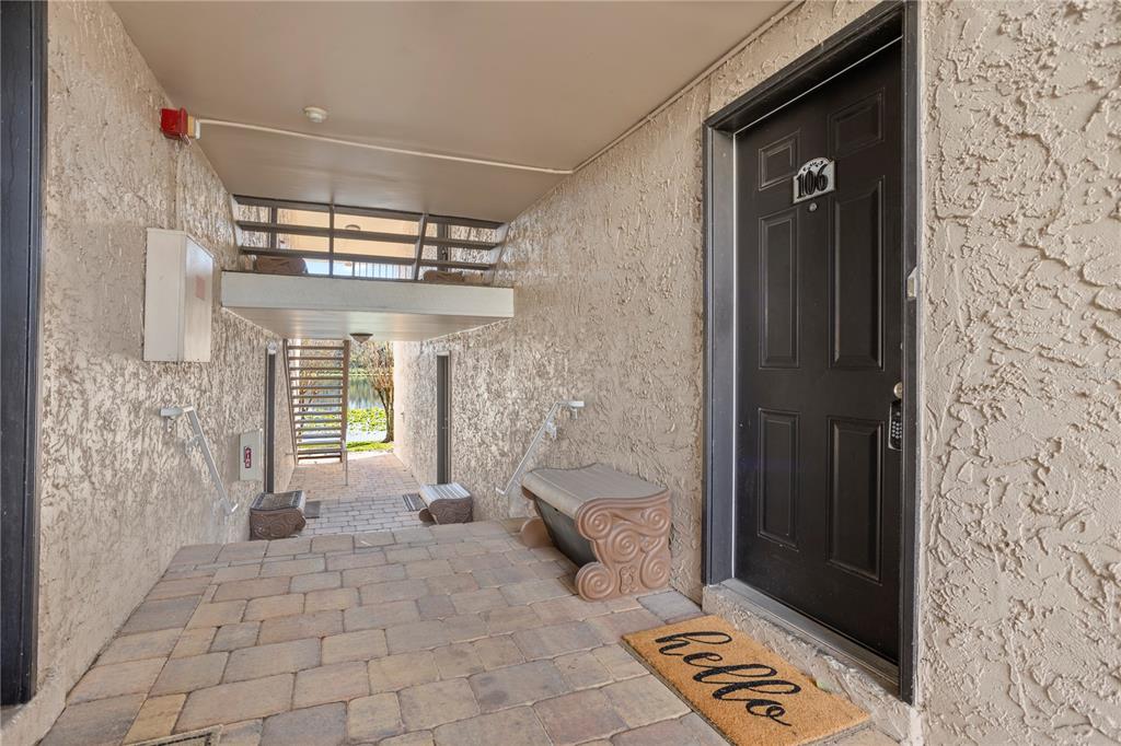 An outdoor entryway with a black door, a hello doormat, and a stone-paved walkway — 145 N PEARL LAKE CAUSEWAY UNIT 106, ALTAMONTE SPRINGS, FL