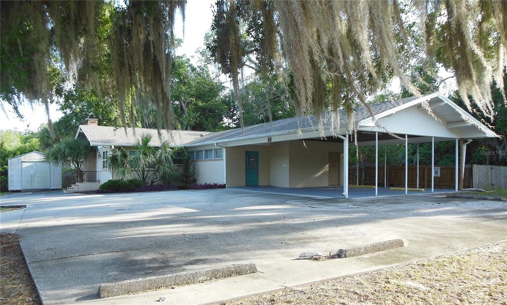 A single-story house with a large concrete driveway, a carport, and a detached storage shed — 500 S DEXTER AVENUE, DELAND, FL