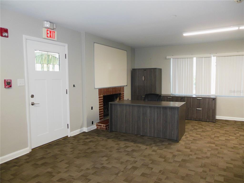 An office space features a desk, a fireplace, a whiteboard, and a white exit door — 500 S DEXTER AVENUE, DELAND, FL
