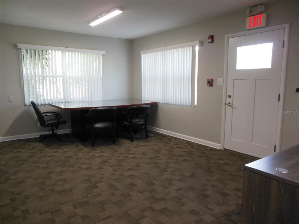 An office room features a conference table, three chairs, vertical blinds, and a white door — 500 S DEXTER AVENUE, DELAND, FL