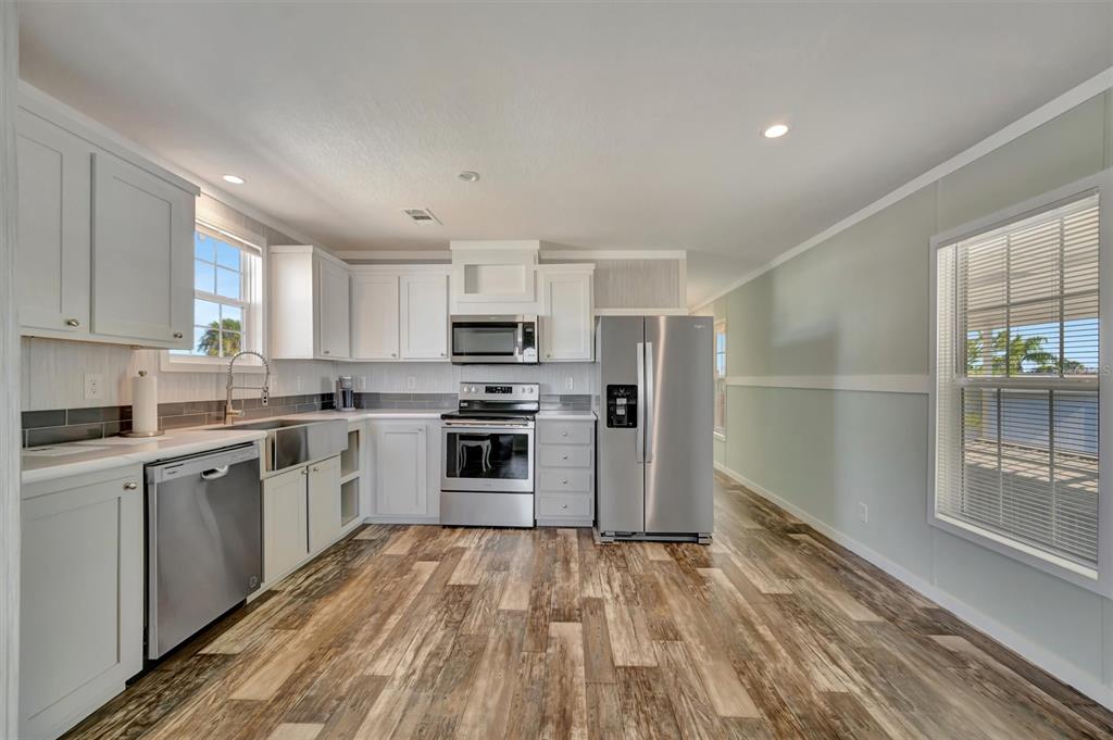 A kitchen with white cabinets, stainless steel appliances, and wood-look flooring — 105 W SAINT JOHNS WAY, APOLLO BEACH, FL