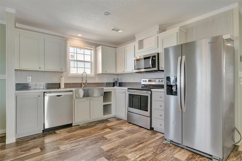 A kitchen featuring light gray cabinets, stainless steel appliances, and wood-look flooring — 105 W SAINT JOHNS WAY, APOLLO BEACH, FL
