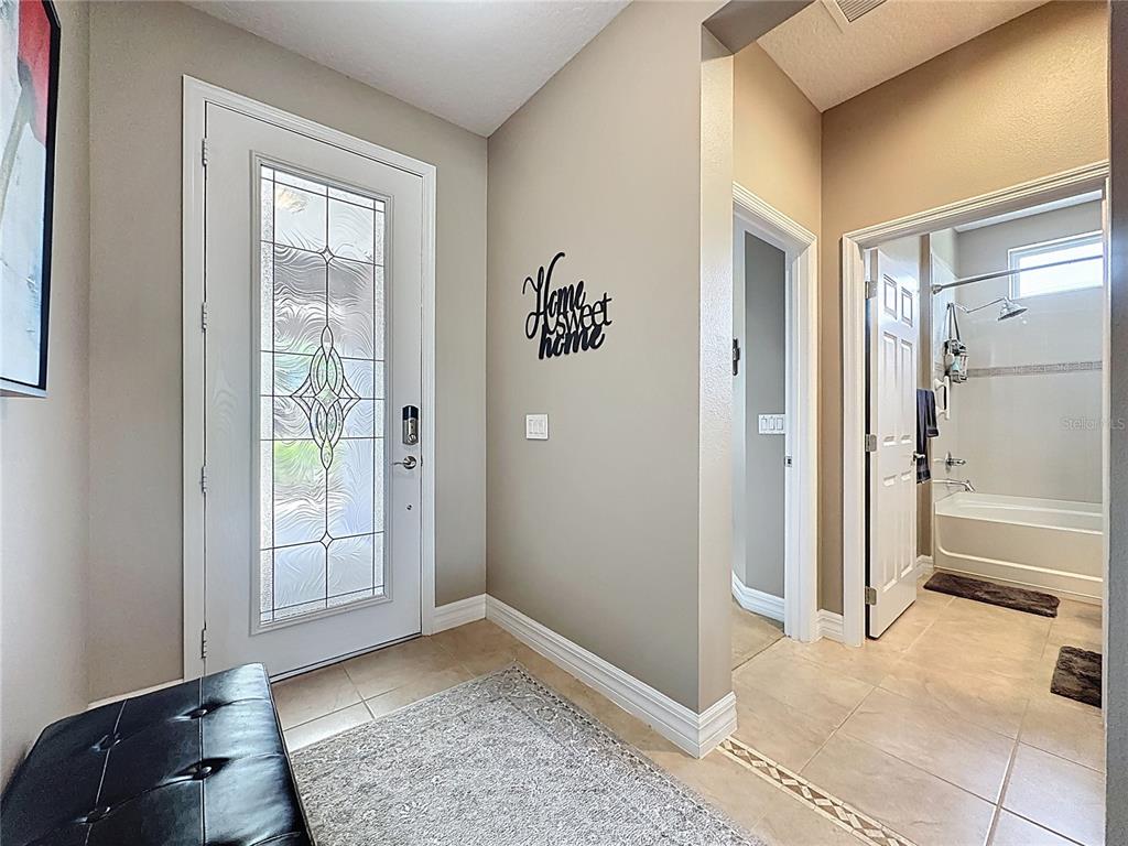 An entryway features a glass-paneled front door, a black bench, and a nearby bathroom door — 108 MIST FLOWER LANE, GROVELAND, FL