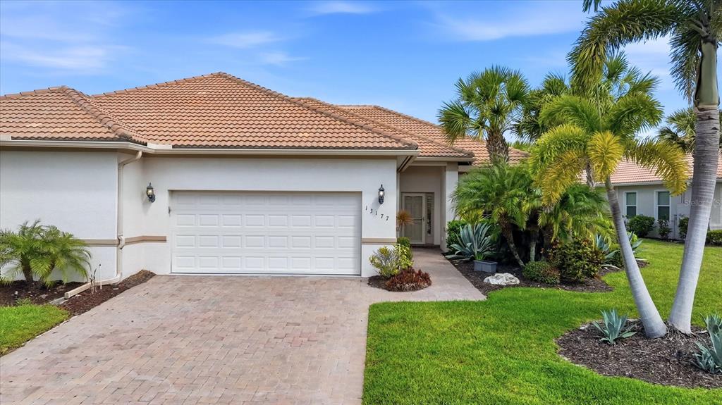 A screened-in pool patio features stone pavers, lounge chairs, and a view of a canal — 13177 CREEKSIDE LANE, PORT CHARLOTTE, FL