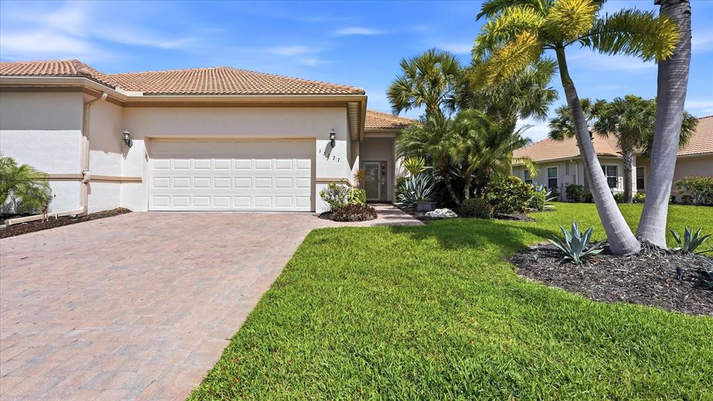 A single-story house with a beige stucco exterior, a tiled roof, and a paved driveway — 13177 CREEKSIDE LANE, PORT CHARLOTTE, FL