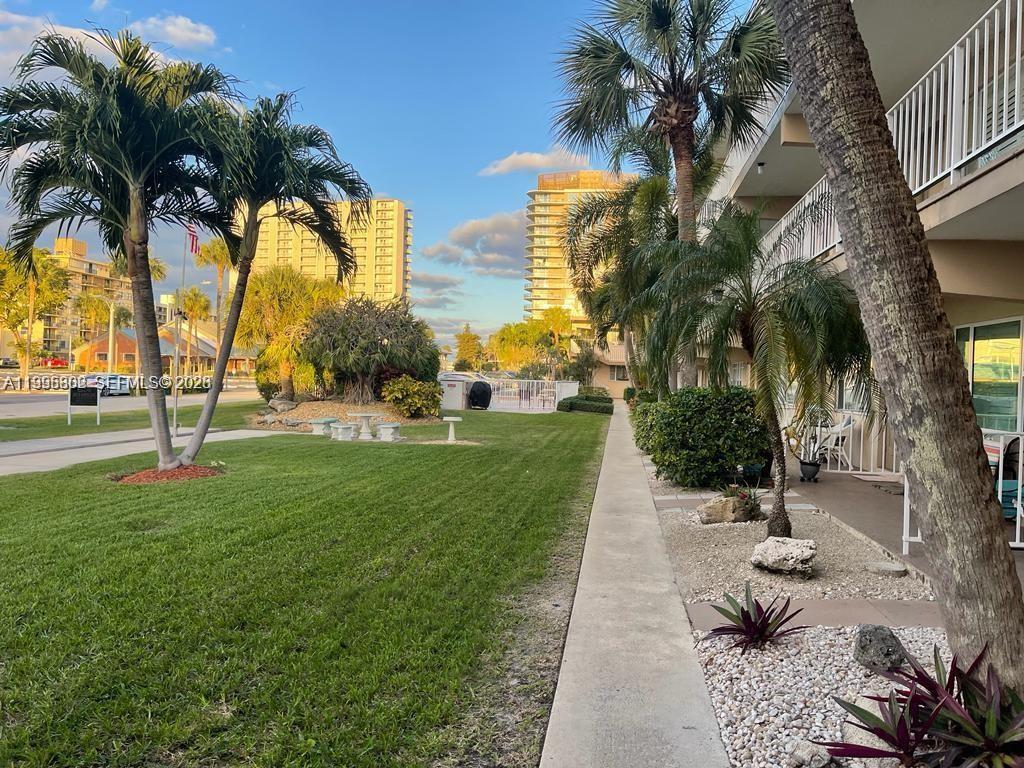 A sidewalk runs alongside a grassy lawn, palm trees, and a multi-story building exterior — 3200 NE 7th Ct # 306C, Pompano Beach FL 33062, POMPANO BEACH, FL
