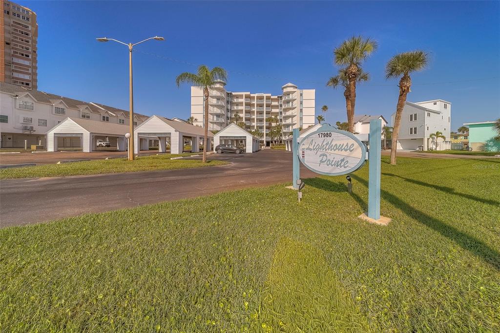 A sign for Lighthouse Pointe stands in front of a multi-story apartment complex and parking — 17980 GULF BOULEVARD UNIT 402, REDINGTON SHORES, FL