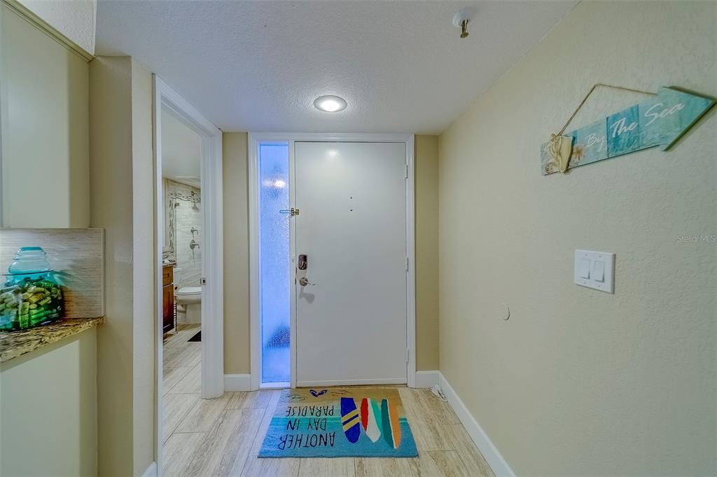 An entryway features a white front door, a side window, and a beach-themed welcome mat — 17980 GULF BOULEVARD UNIT 402, REDINGTON SHORES, FL