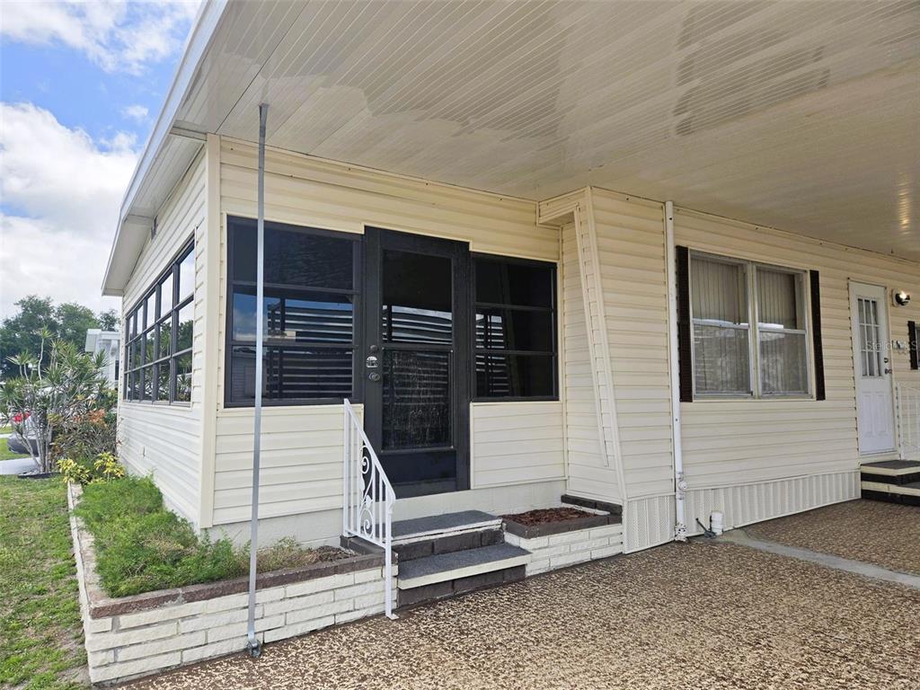 A light-colored mobile home exterior features a screened-in porch, a carport, and concrete steps — 3226 SWEET GUM TERRACE, SARASOTA, FL