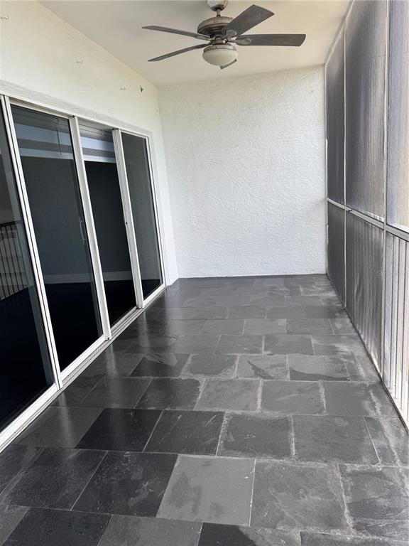 A screened-in balcony features dark slate tile flooring, a ceiling fan, and sliding glass doors — 1200 COUNTRY CLUB DRIVE UNIT 2405, LARGO, FL
