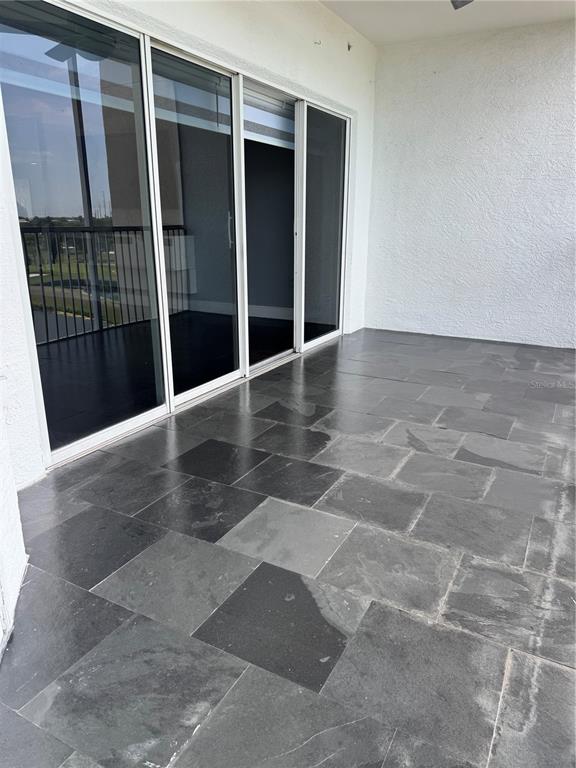A covered patio features dark stone tile flooring and large sliding glass doors — 1200 COUNTRY CLUB DRIVE UNIT 2405, LARGO, FL