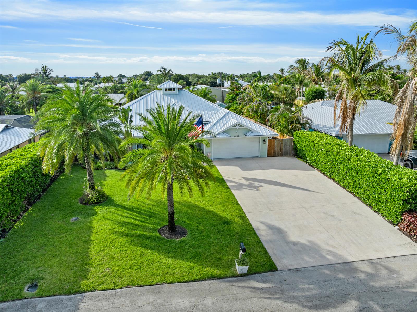 A single-story house with a metal roof, palm trees, and a concrete driveway — 4689 SE Glen Ridge Trail, Stuart FL 34997, STUART, FL