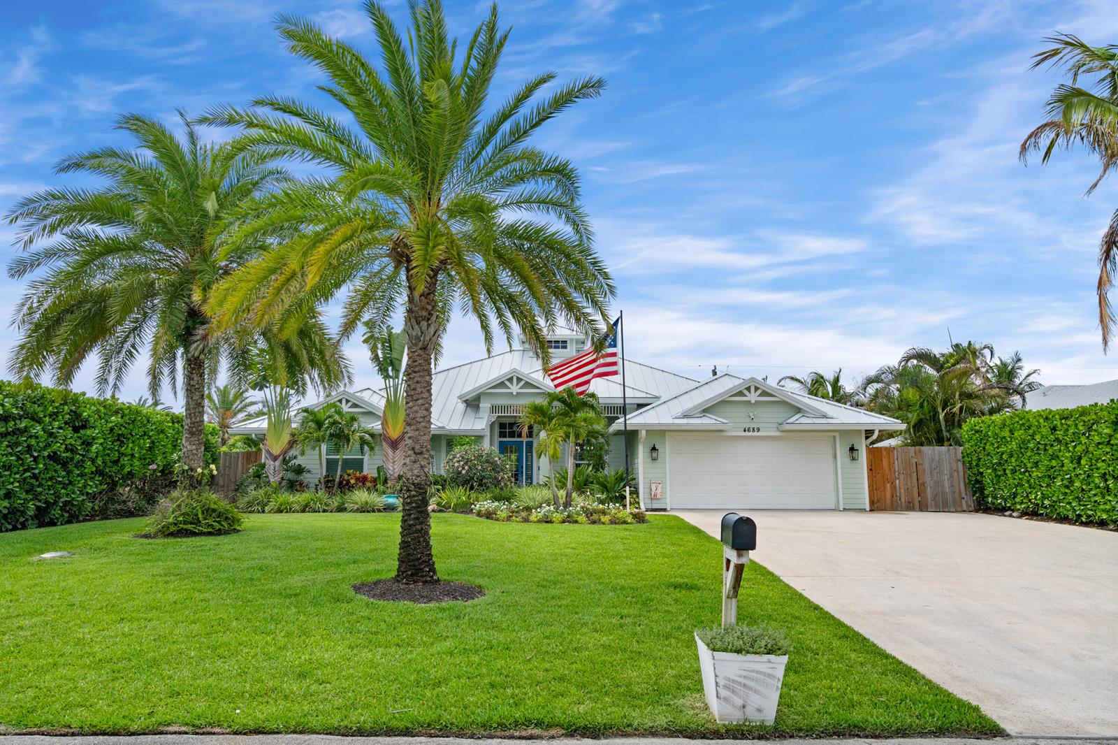 A light green single-story house with a metal roof, palm trees, and a front lawn — 4689 SE Glen Ridge Trail, Stuart FL 34997, STUART, FL