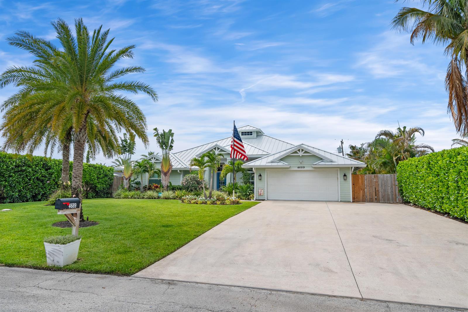 A light green single-story house with a metal roof and a large concrete driveway — 4689 SE Glen Ridge Trail, Stuart FL 34997, STUART, FL