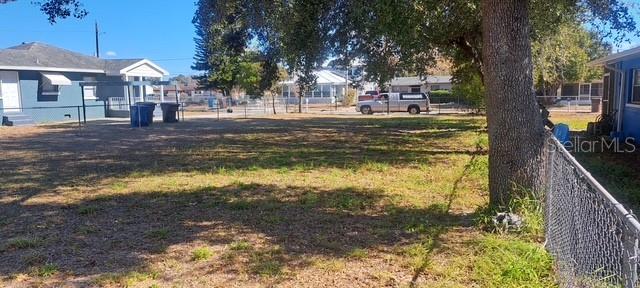 A vacant, grassy residential lot is enclosed by a chain-link fence near a house — 0 PEARL STREET, LAKE WALES, FL