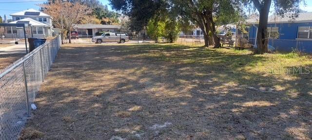 A grassy, fenced-in vacant lot sits in a residential neighborhood with houses in the background — 0 PEARL STREET, LAKE WALES, FL