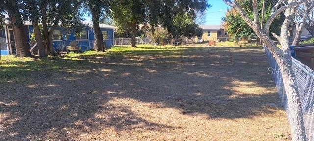 A large, flat, grassy residential lot with trees and a chain-link fence — 0 PEARL STREET, LAKE WALES, FL