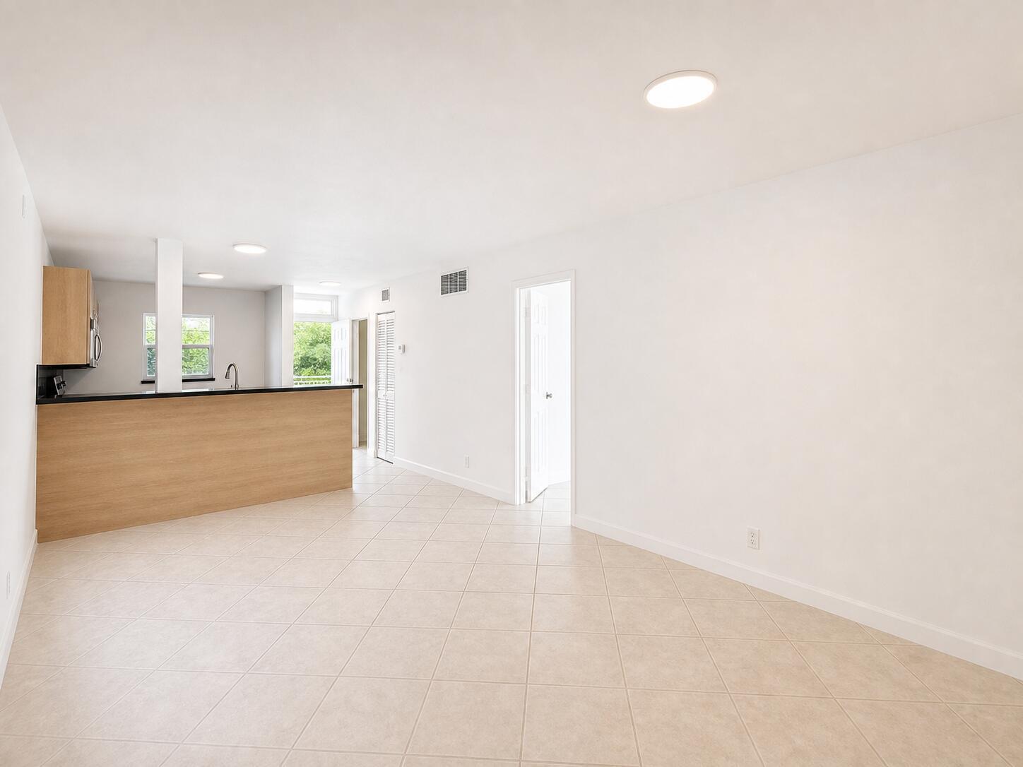 An open-concept living area features light wood cabinetry, a black countertop, and beige tile flooring — 1541 S Ocean Boulevard # 219, Pompano Beach FL 33062, POMPANO BEACH, FL
