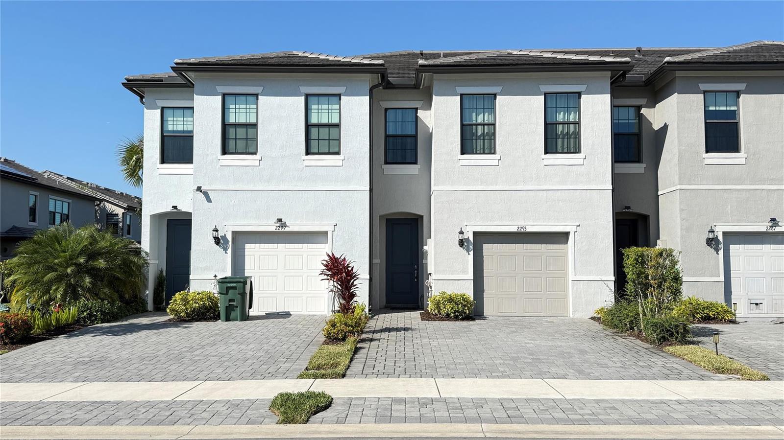 A two-story townhouse exterior features white stucco walls, gray garage doors, and paved driveways — 2293 S Appleton Circle, Oakland Park FL 33309, OAKLAND PARK, FL