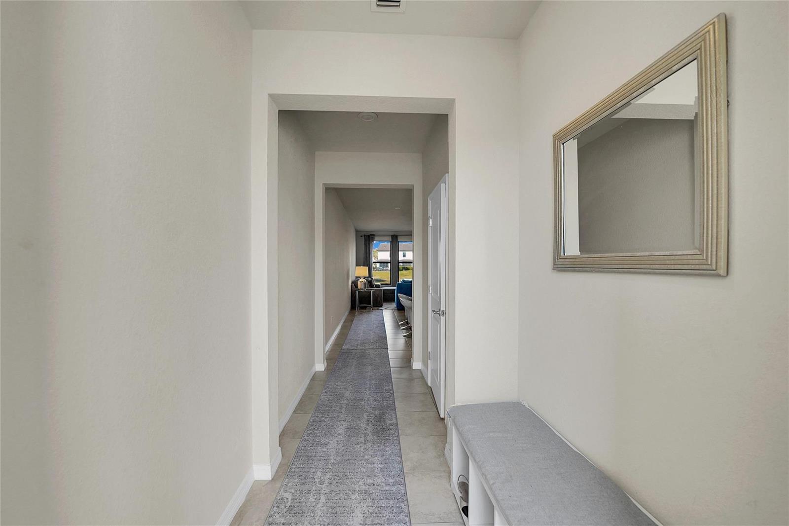 A hallway features a long runner rug, a wall-mounted mirror, and a storage bench — 2293 S Appleton Circle, Oakland Park FL 33309, OAKLAND PARK, FL