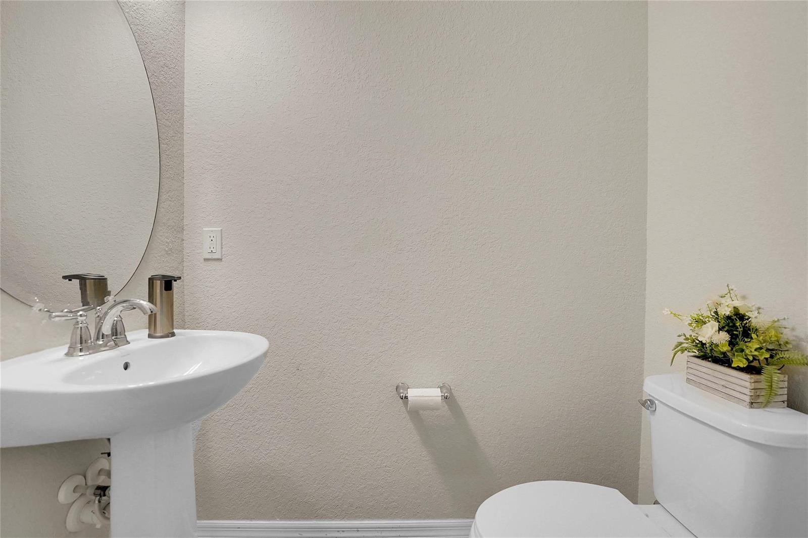 A bathroom features a pedestal sink, a round mirror, a toilet, and a wall-mounted holder — 2293 S Appleton Circle, Oakland Park FL 33309, OAKLAND PARK, FL