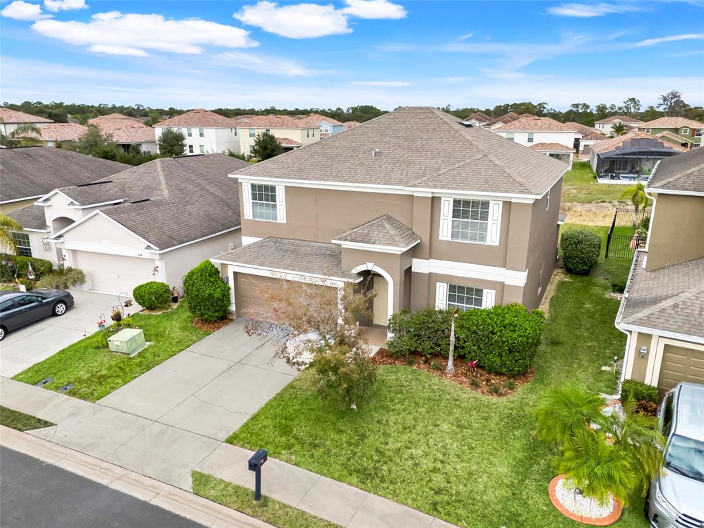 An aerial view shows a two-story tan suburban house with a brown roof and driveway — 3560 CORTLAND DRIVE, DAVENPORT, FL
