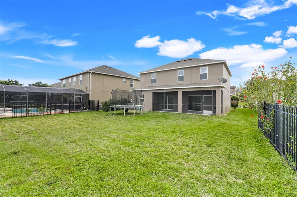 The backyard features a grassy lawn, a trampoline, and two houses with screened-in patios — 3560 CORTLAND DRIVE, DAVENPORT, FL