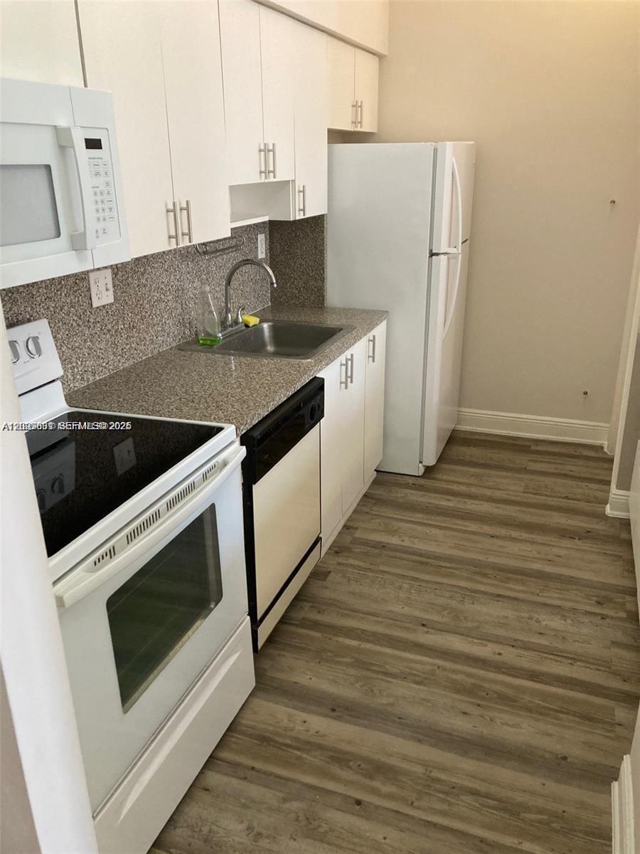 A kitchen features white cabinets, granite countertops, a white stove, and light wood-look flooring — 7420 W 20th Ave # 151, Hialeah FL 33016, HIALEAH, FL