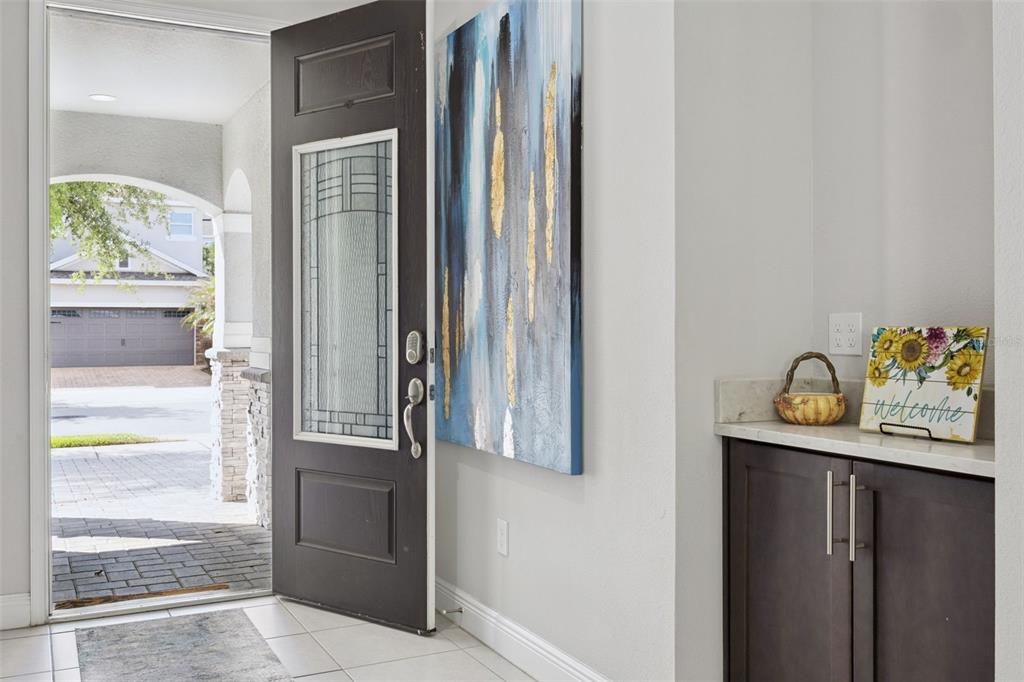 An entryway features a dark wood door, abstract wall art, and a small storage cabinet — 7457 MARKER AVENUE, KISSIMMEE, FL