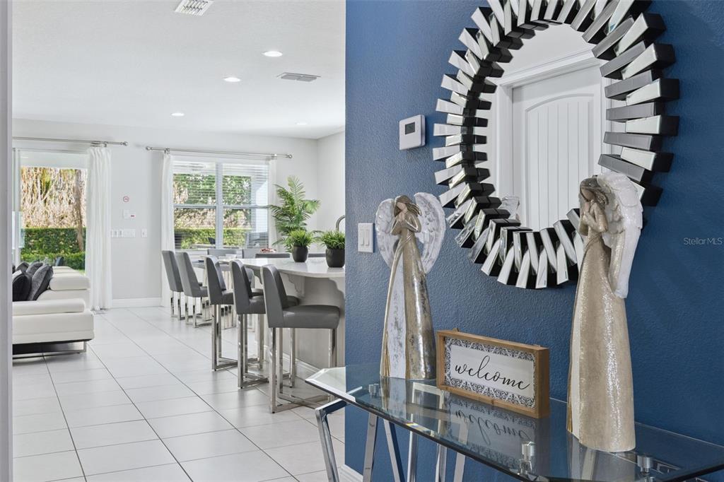 A blue entryway with a mirror and angel figurines leads into a bright open kitchen — 7457 MARKER AVENUE, KISSIMMEE, FL