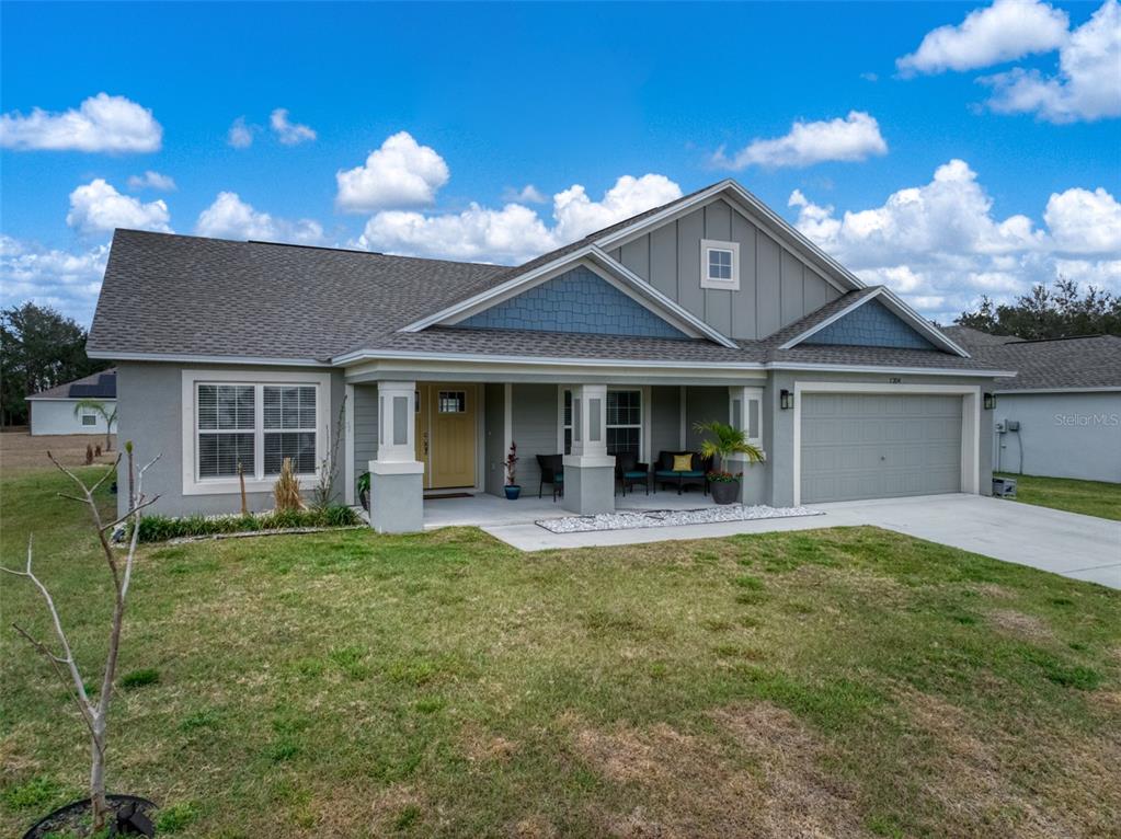 A single-story house with a gray exterior, blue shingle accents, and a covered front porch — 1204 RIDGE DRIVE, AVON PARK, FL